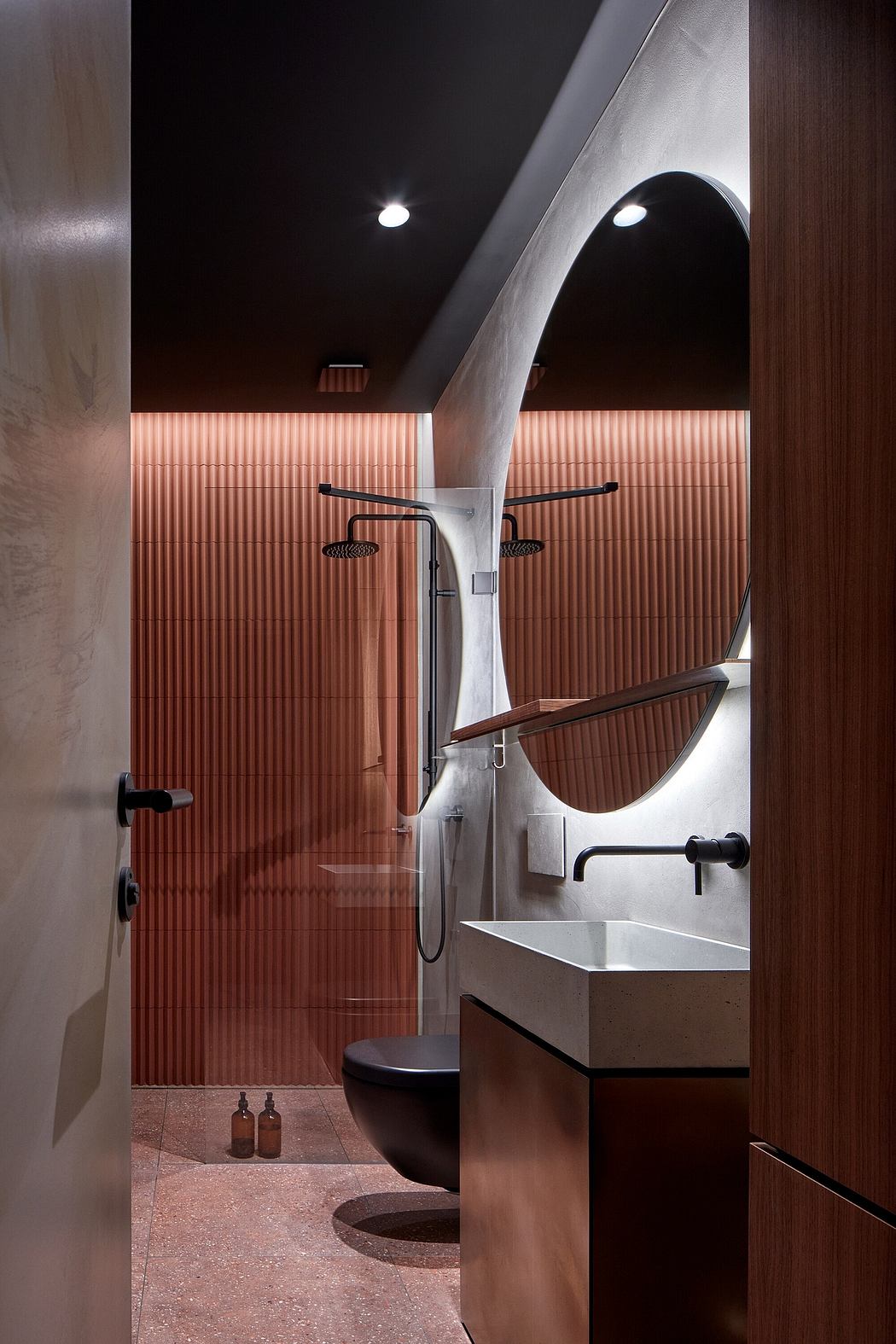 Sleek, modern bathroom design featuring bold red walls, arched mirrors, and sculptural sink.