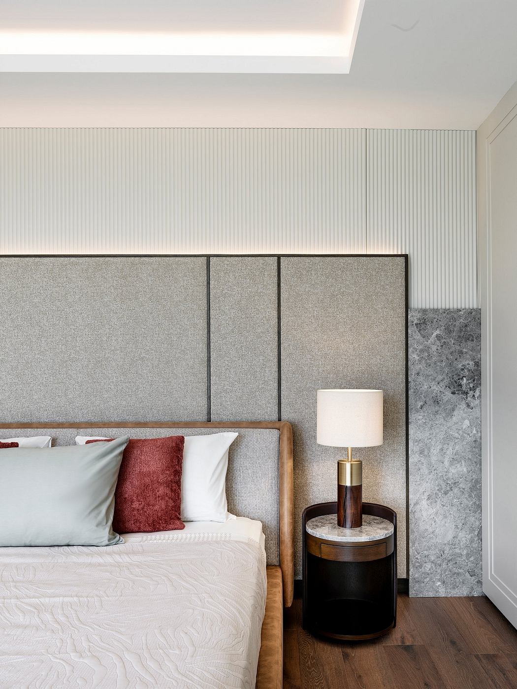 Sleek, minimalist bedroom with textured paneling, marble accent, and modern table lamp.