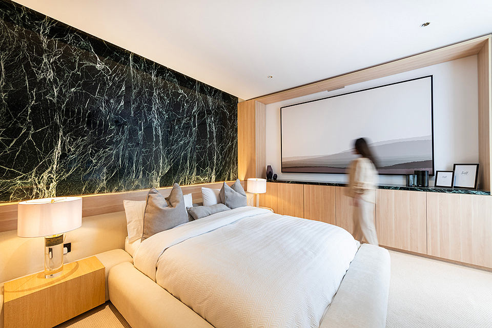 Luxurious bedroom with sleek wood paneling, dark marble accent wall, and built-in shelving.