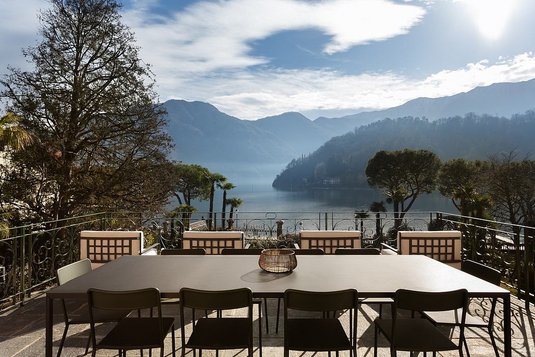 Elegant outdoor dining area with panoramic lake and mountain views, featuring modern furnishings.