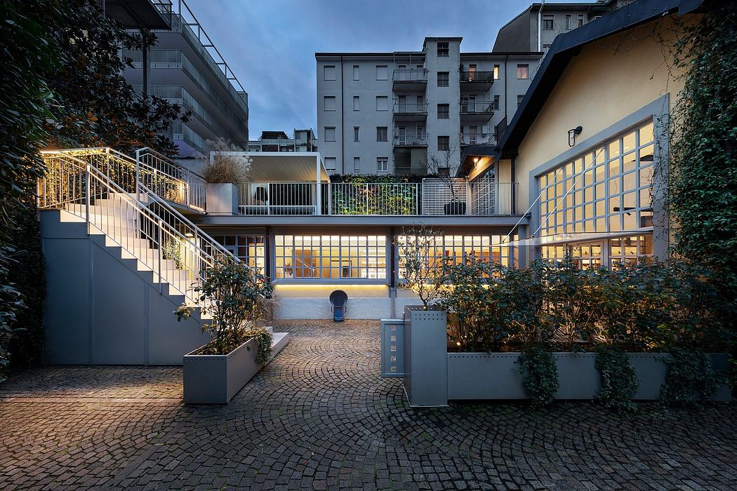 Illuminated entrance and courtyard of a modern apartment building with glass walls.