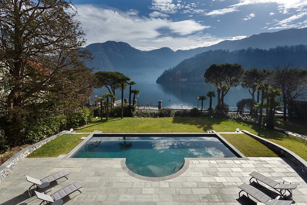Serene lakefront property with manicured gardens, infinity pool, and mountain vistas.