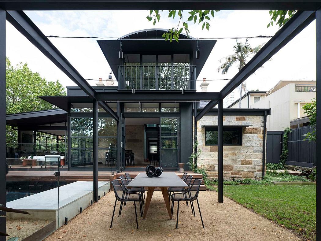 An open-concept modern home with a large covered patio, wooden deck, and stone walls.