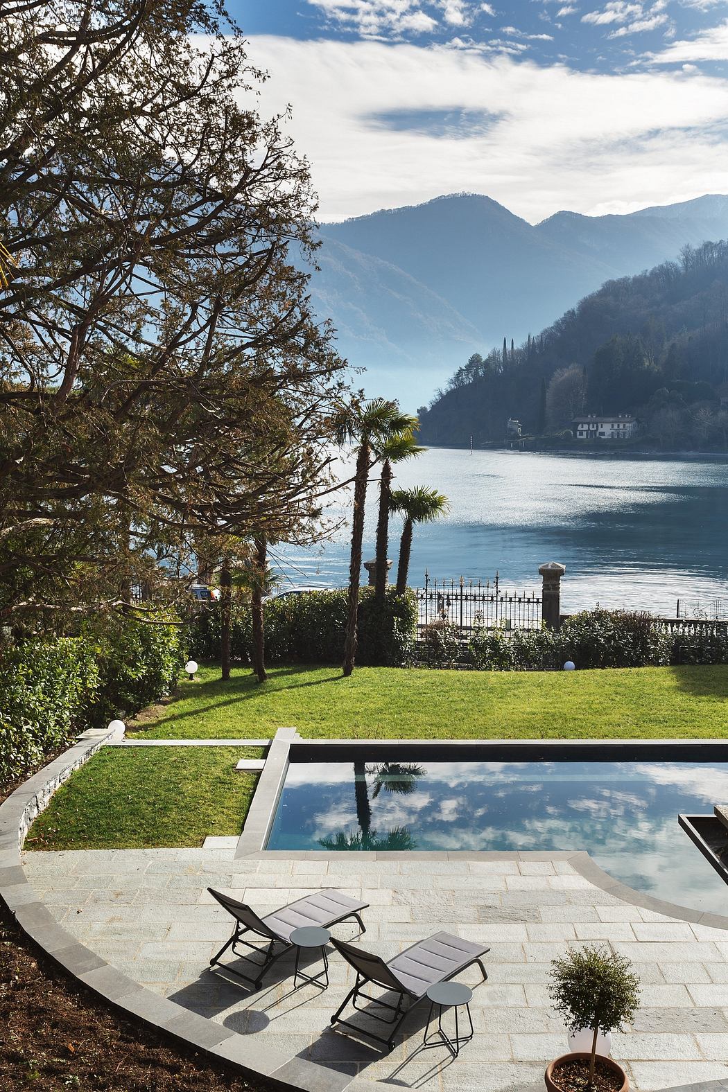 Serene lakeside oasis with sleek infinity pool, lush greenery, and towering mountain views.