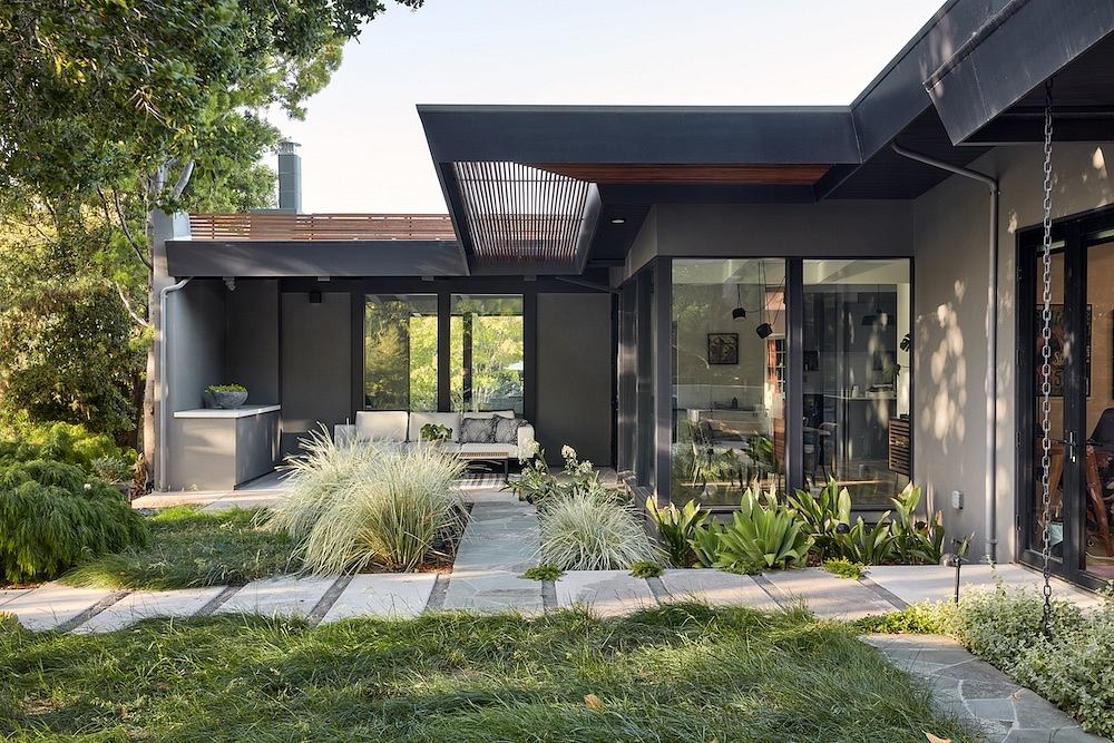 Sleek, modern home exterior with glass walls, wooden accents, and lush landscaping.