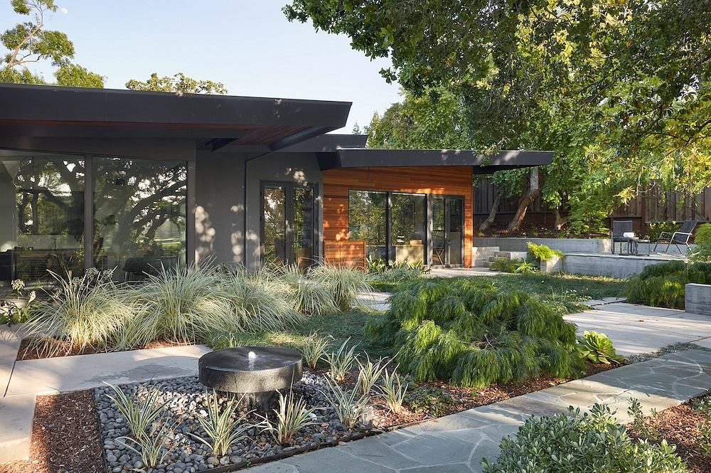 A contemporary outdoor living space with a sleek, glass-walled structure and lush landscaping.