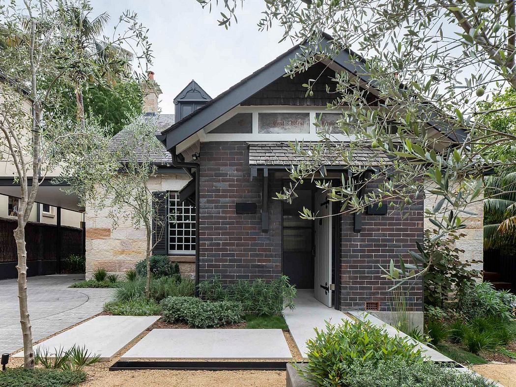 Charming brick cottage with a gabled roof, surrounded by lush greenery.