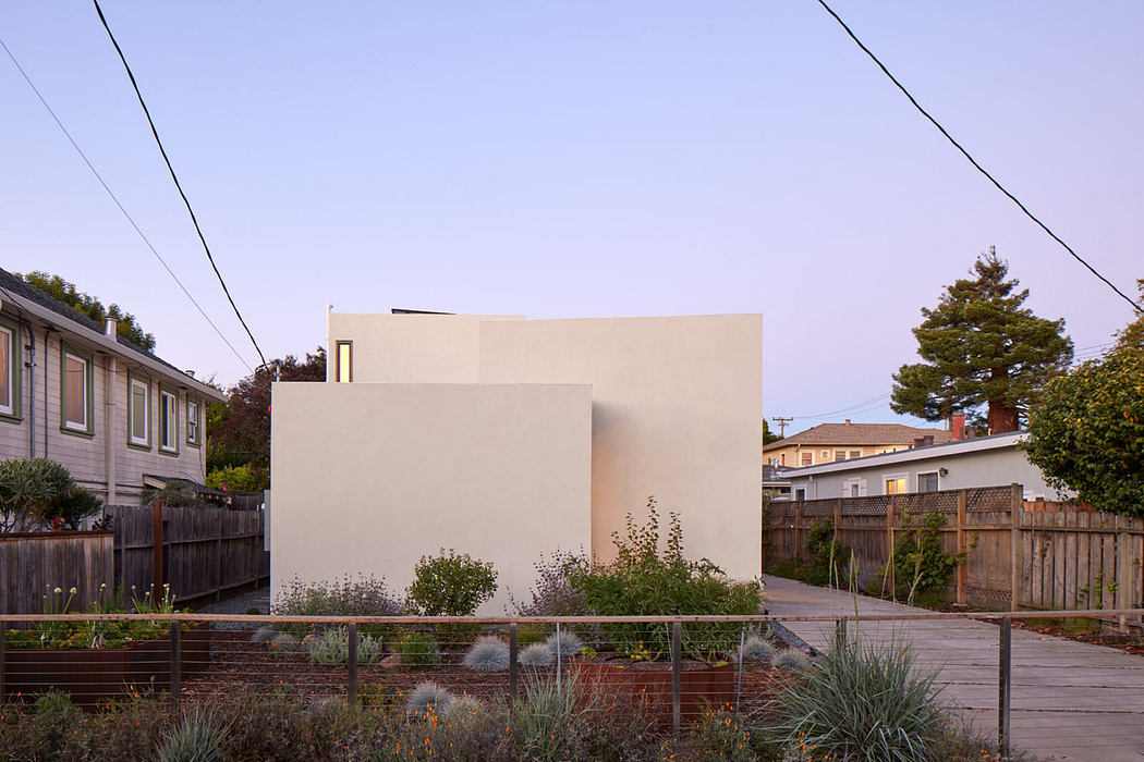 Minimalist modern home with geometric facade, surrounded by lush landscaping.