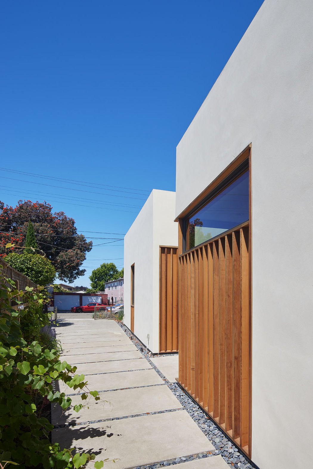 A modern, minimalist architecture with wooden accents and a paved walkway leading to the building.