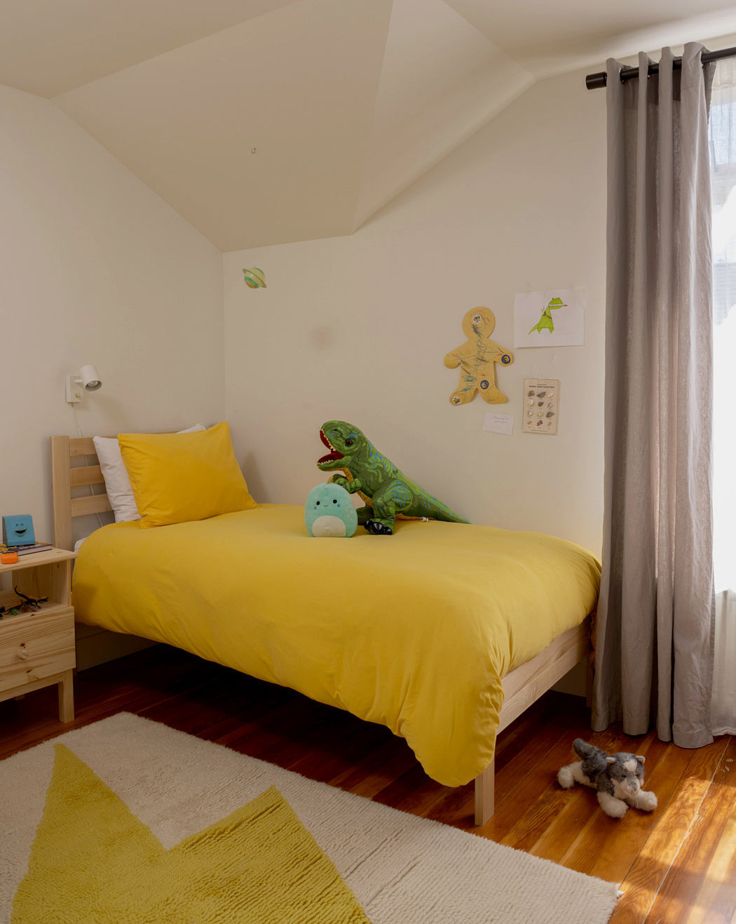 Cozy, child-friendly bedroom with yellow bedding, plush toys, and warm wooden furniture.
