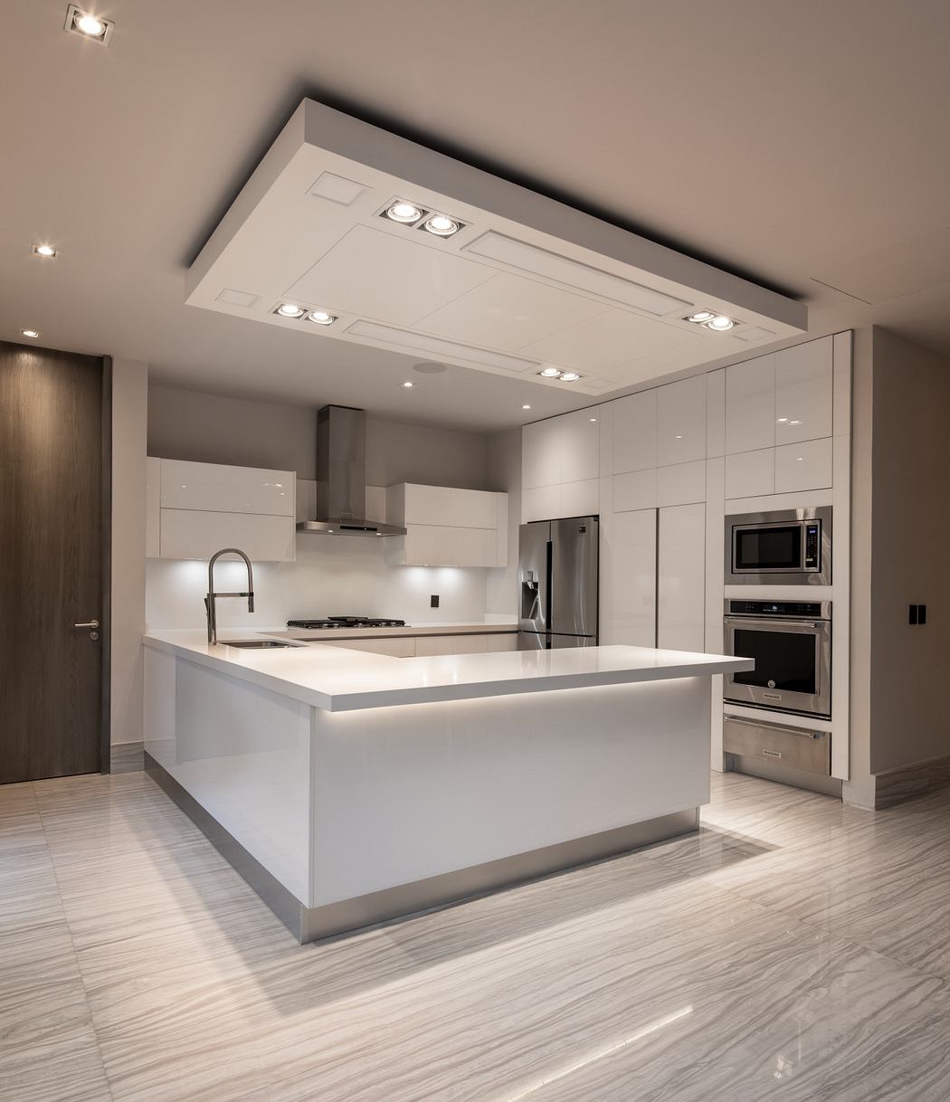 Sleek, modern kitchen with large central island, recessed lighting, and stainless steel appliances.