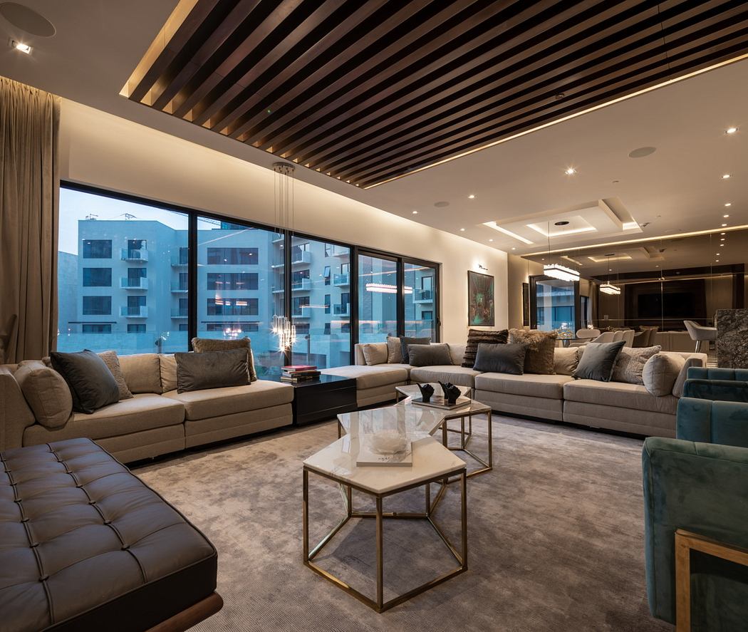 Luxurious high-ceiling living room with sleek wood beams, large windows, and plush furnishings.