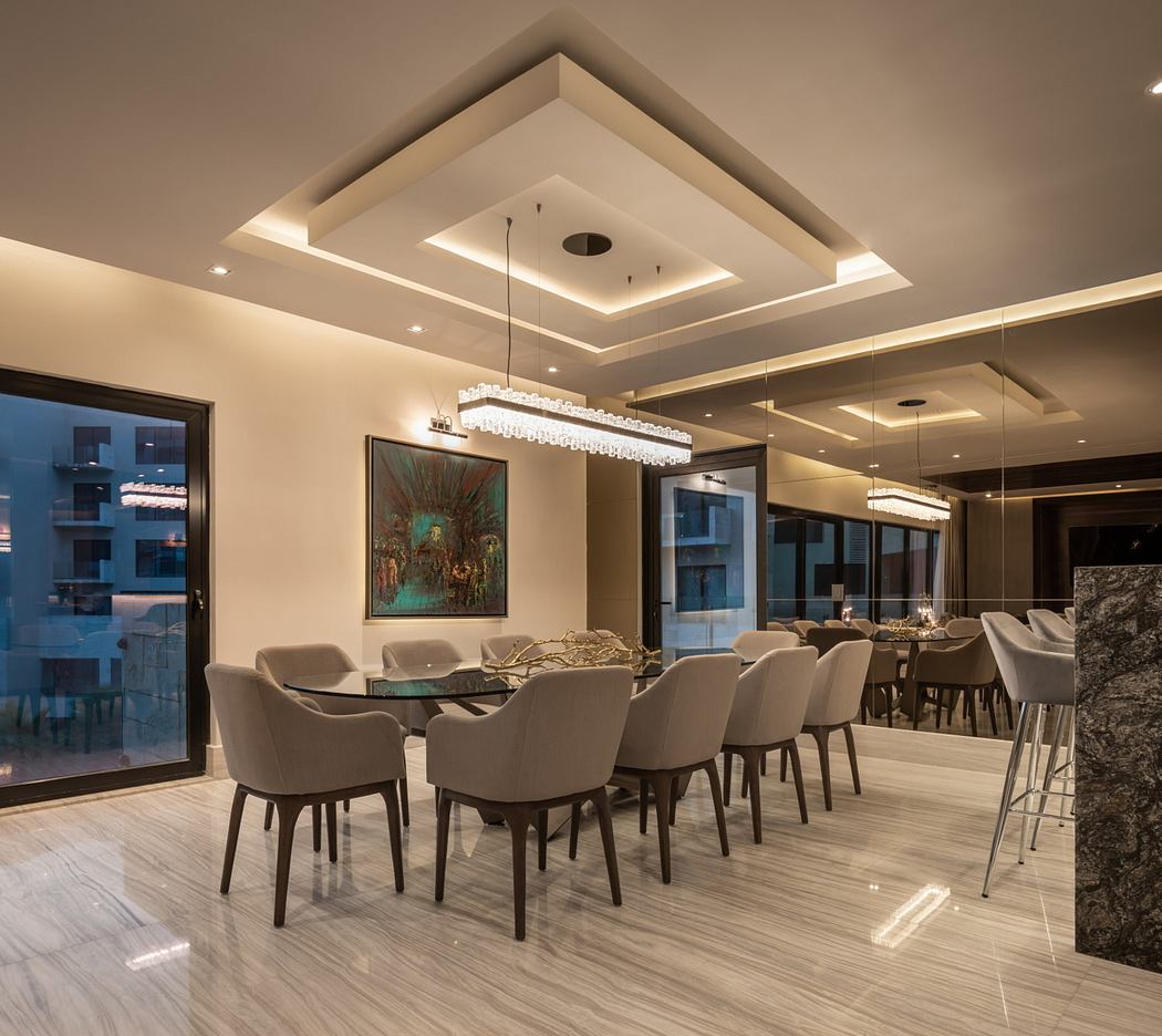 Luxurious dining space with geometric ceiling design, modern furnishings, and artwork.