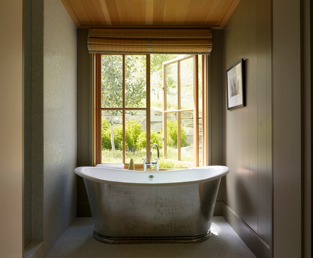 Spacious bathroom with freestanding bathtub, large window overlooking lush greenery.