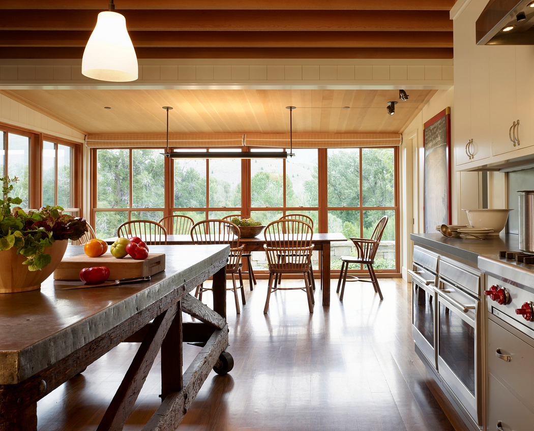 Spacious kitchen with large windows, wooden beams, and a rustic dining table.