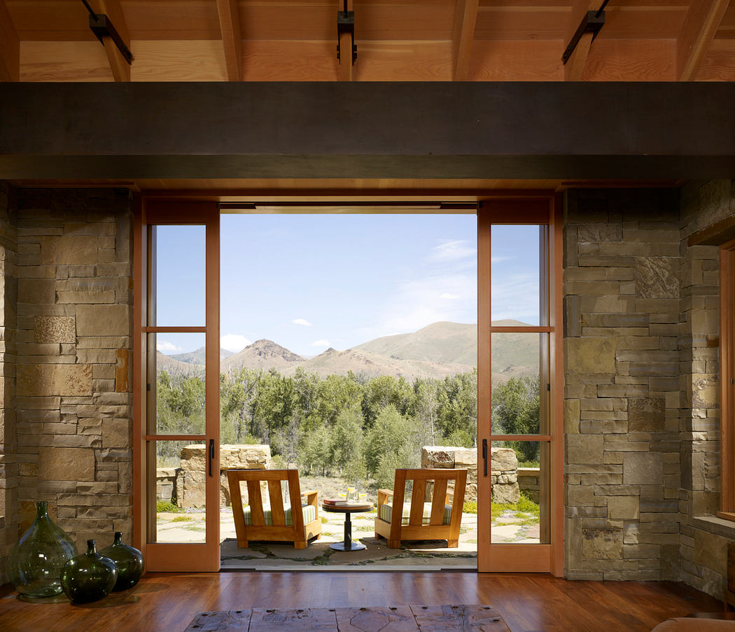 A cozy, rustic living space with large windows framing a stunning mountain landscape.