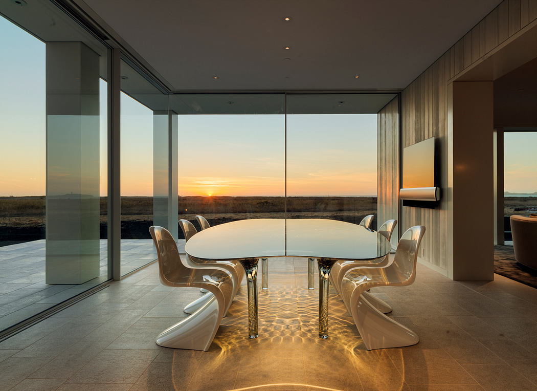 Lavish modern dining space with sleek furniture, floor-to-ceiling windows, and a breathtaking sunset view.