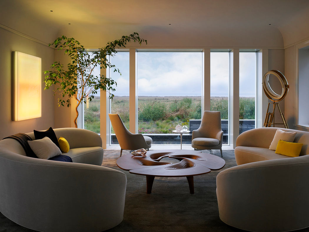 Spacious minimalist living room with large windows offering scenic countryside views.