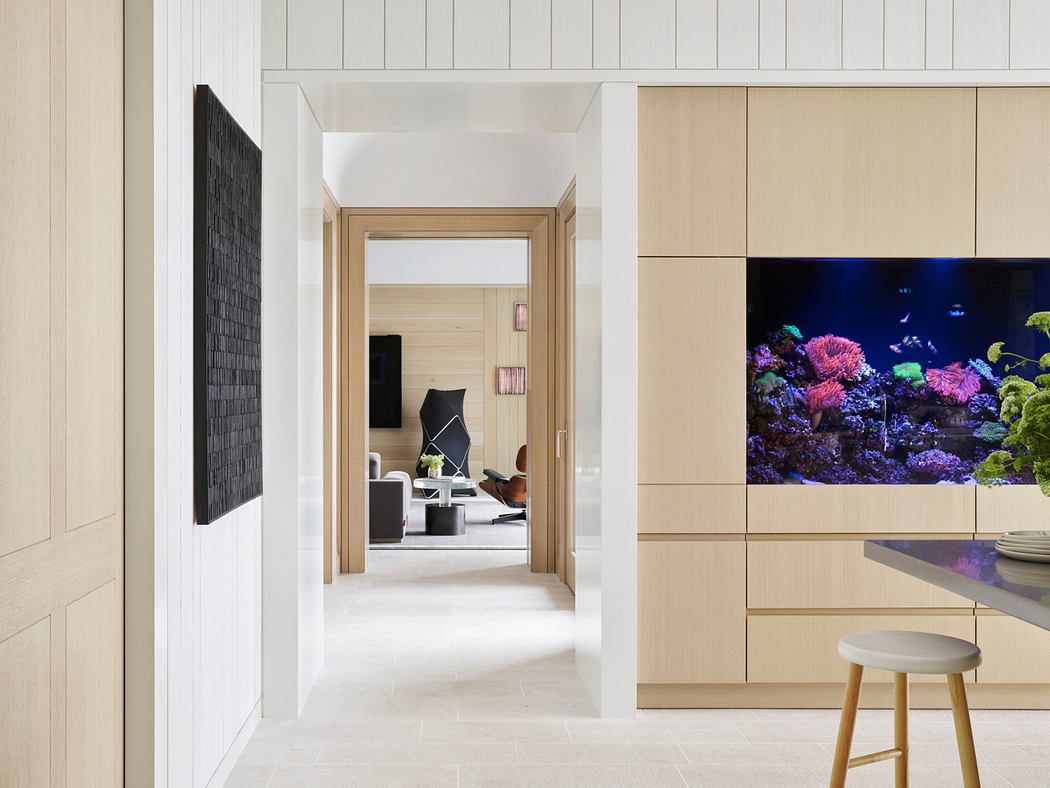 A modern, minimalist interior with an aquarium and built-in wooden cabinetry.