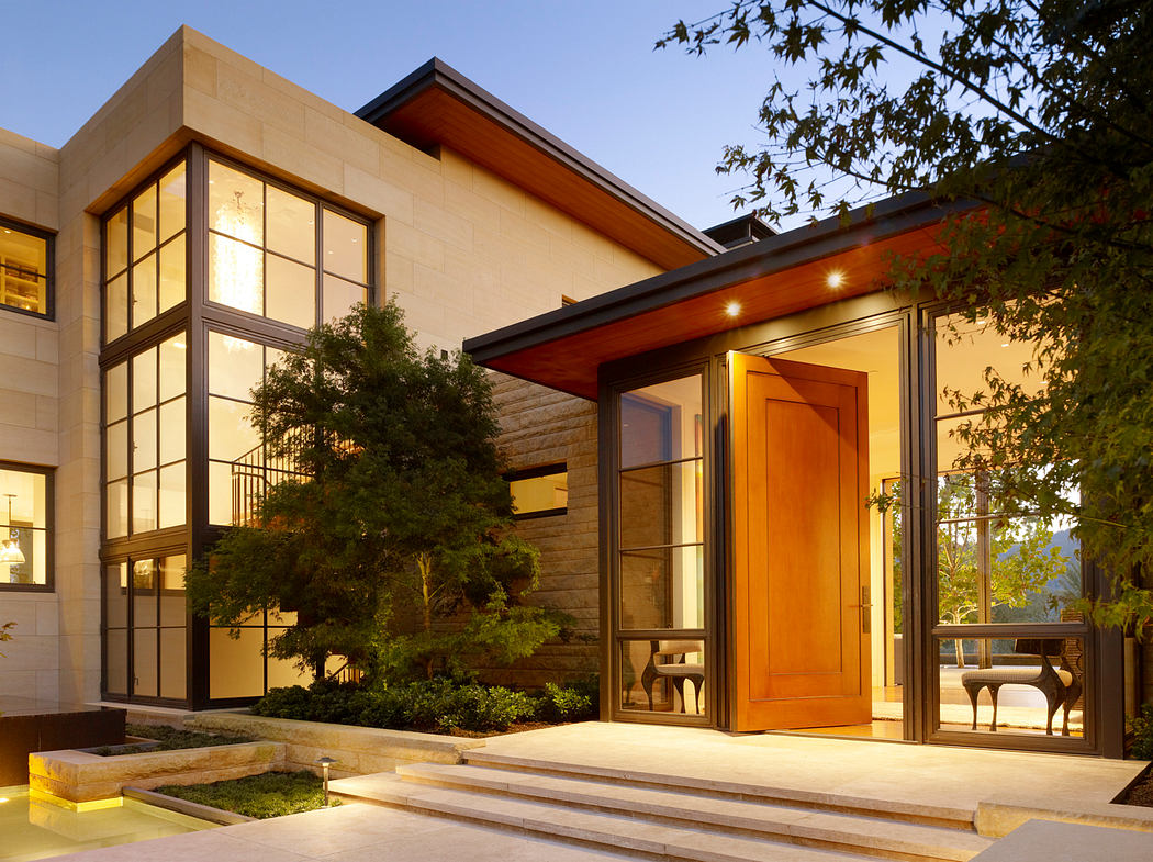 Elegant modern home with expansive windows, wooden beams, and landscaped entrance.