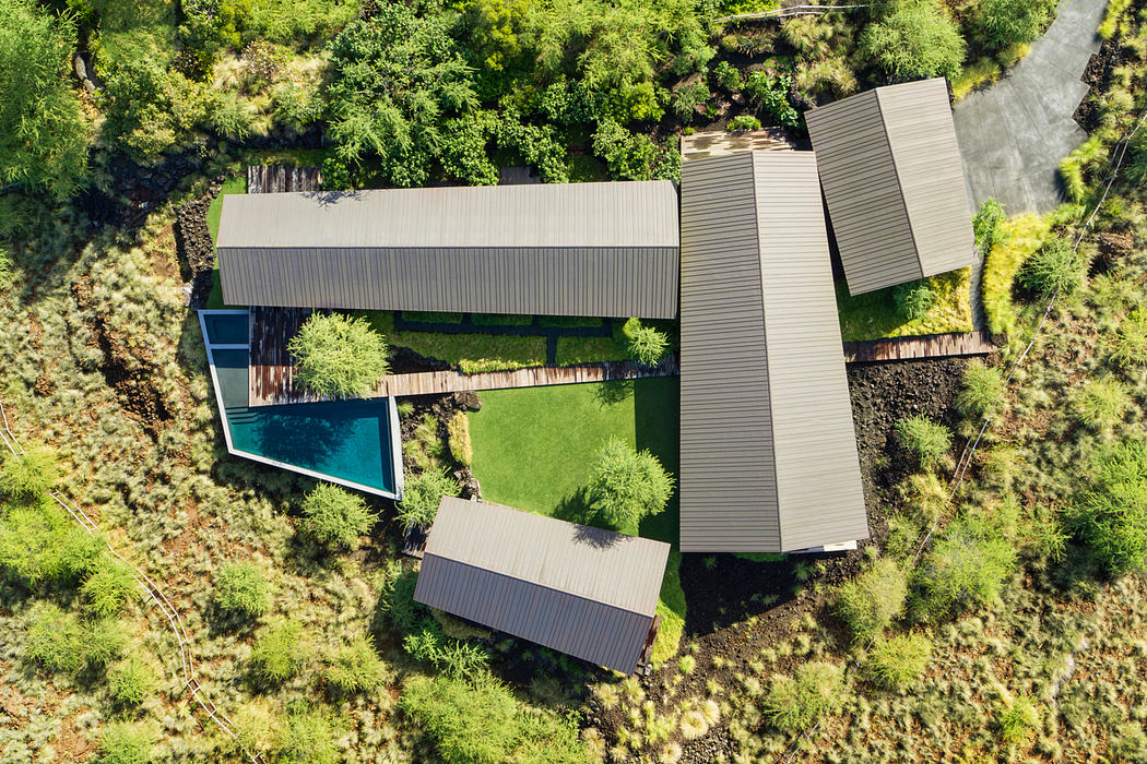 A modern, angular home nestled in a lush, green landscape with a pool and multiple levels.