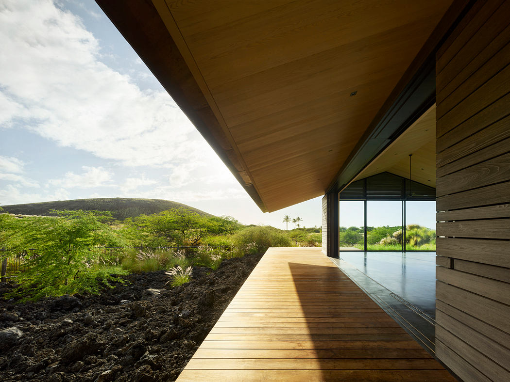 Wooden walkway leading to a modern glass-walled structure with a serene landscape view.