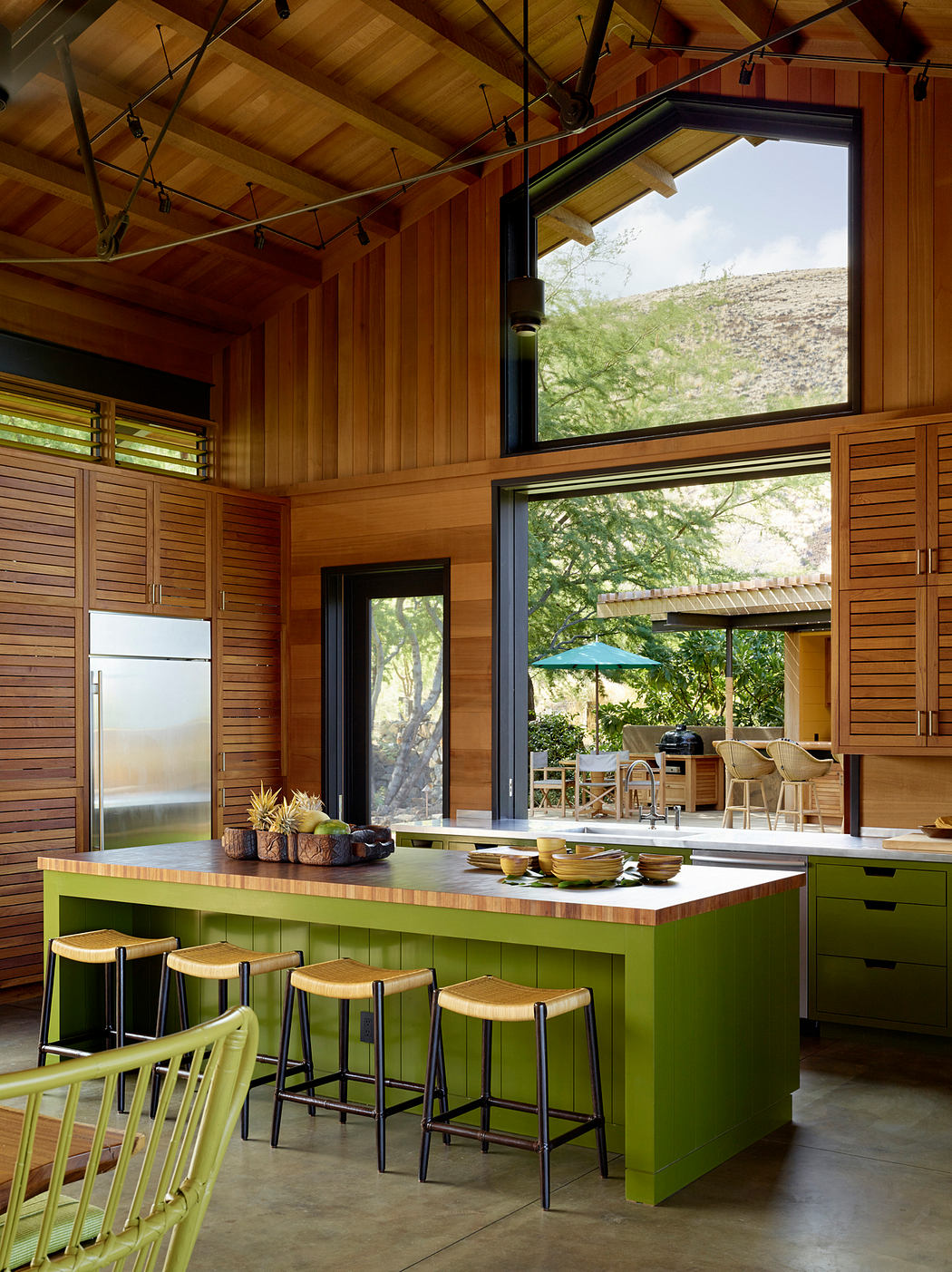 Rustic wooden cabin with a modern green kitchen island and sliding glass doors overlooking nature.