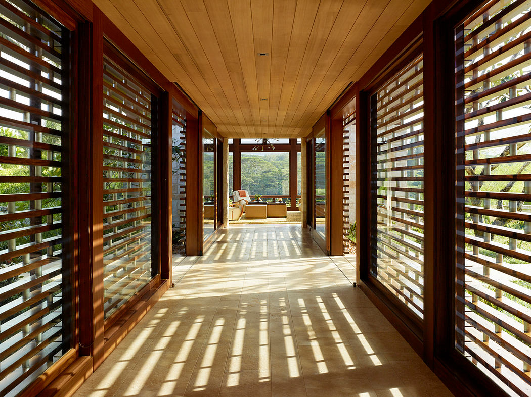 Warm, wooden ceiling and panels line an airy, sun-filled hallway with a cozy lounge beyond.