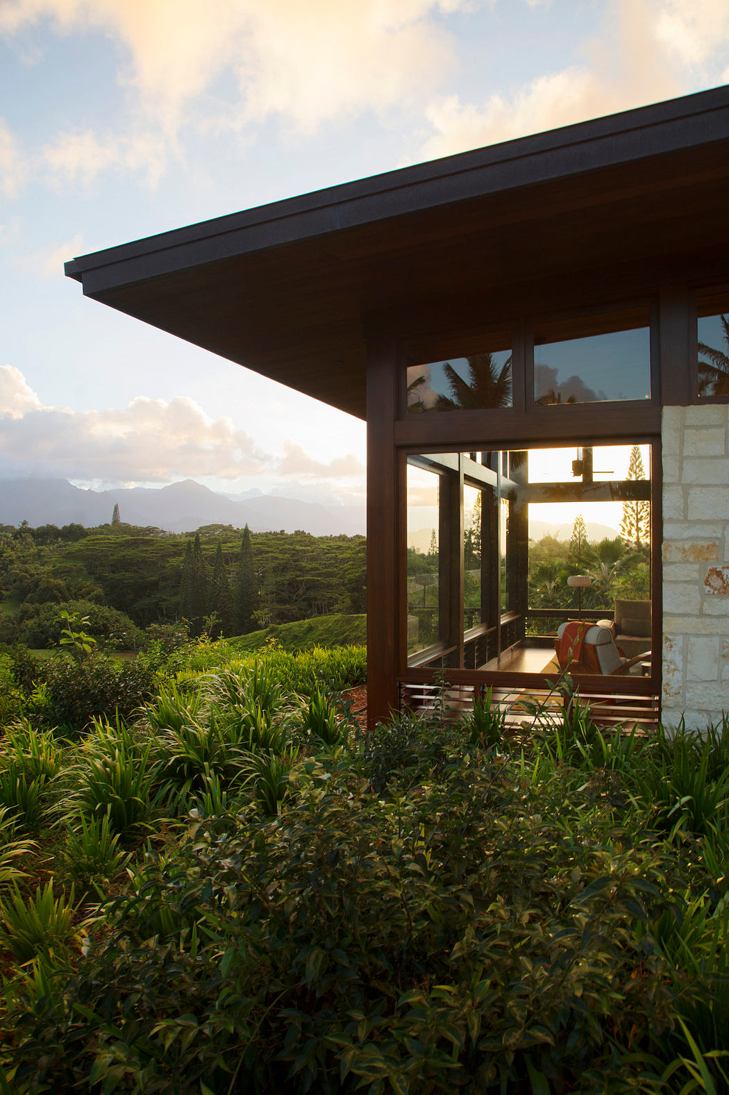A modern, glass-walled structure nestled in a lush, tropical landscape, offering a scenic view.