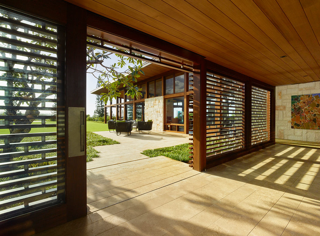 Inviting covered porch with slatted wooden screens and expansive views of a grassy lawn.