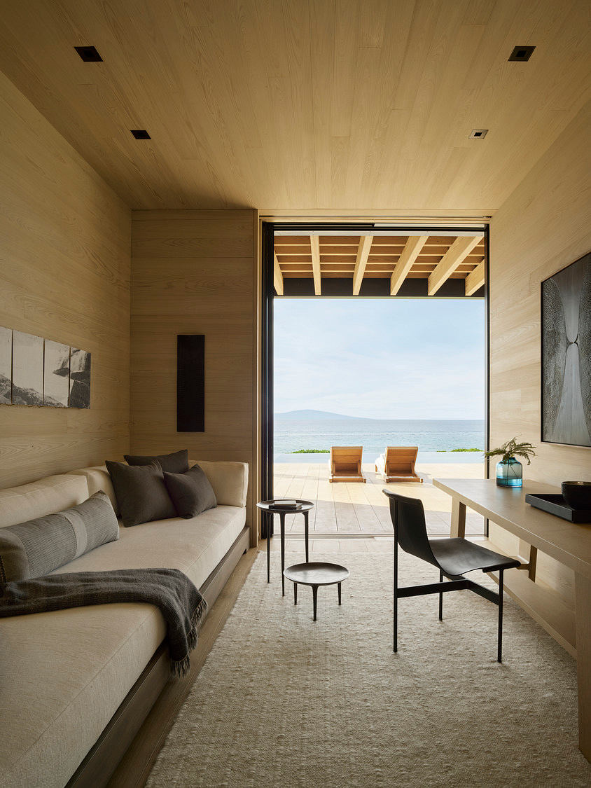 Minimalist living space with expansive ocean views, natural wood ceiling, and neutral furniture.