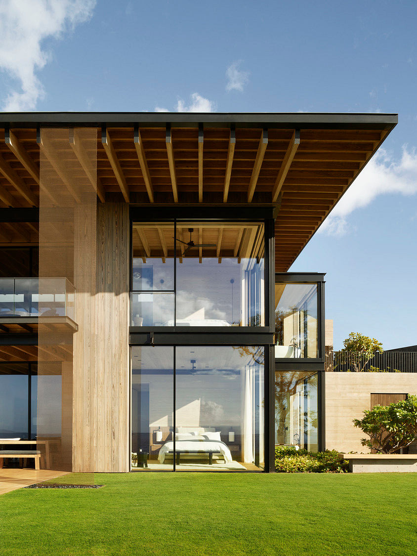 Wooden structure with slanted roof, large glass panels, and landscaped exterior.