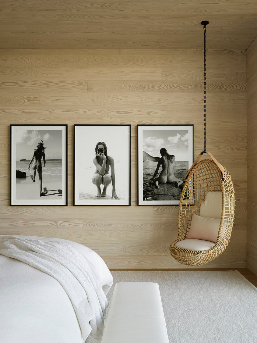 Serene bedroom with wooden walls, minimalist decor, and a cozy hanging chair.