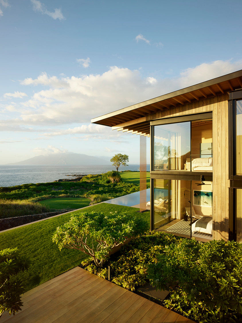 Striking modern architecture with wooden deck overlooking scenic coastal landscape.