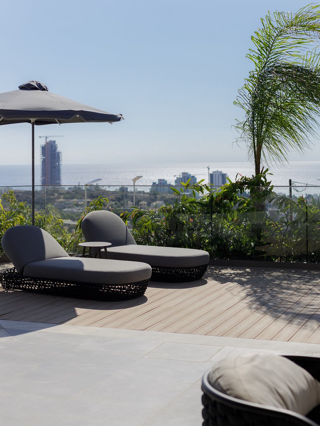 Modern outdoor lounge area with canopy, wicker furniture, and city skyline view.