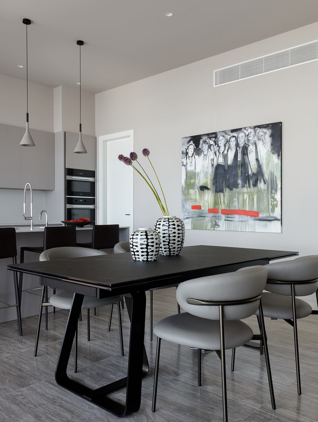 Sleek modern dining room with black table, minimalist pendants, and bold artwork.