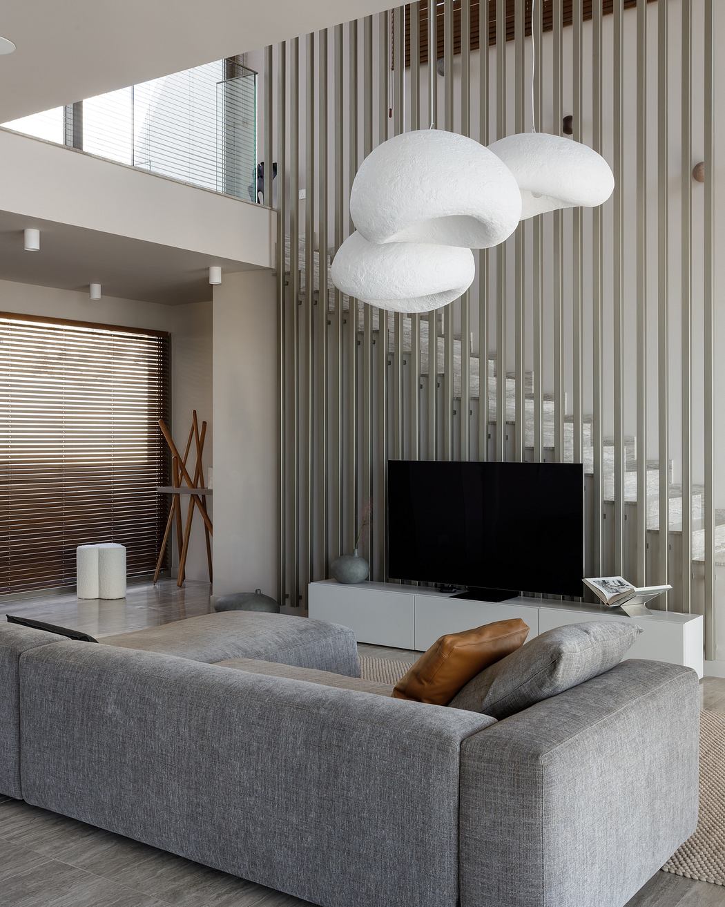 Modern living room with sleek gray sofa, minimalist lighting fixtures, and vertical slatted wall panels.