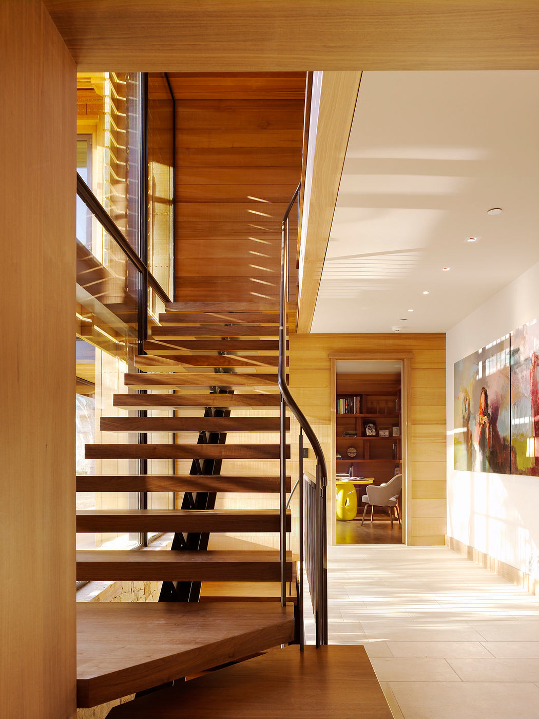 Warm wooden staircase with sleek metal railings leading to an open, light-filled space.