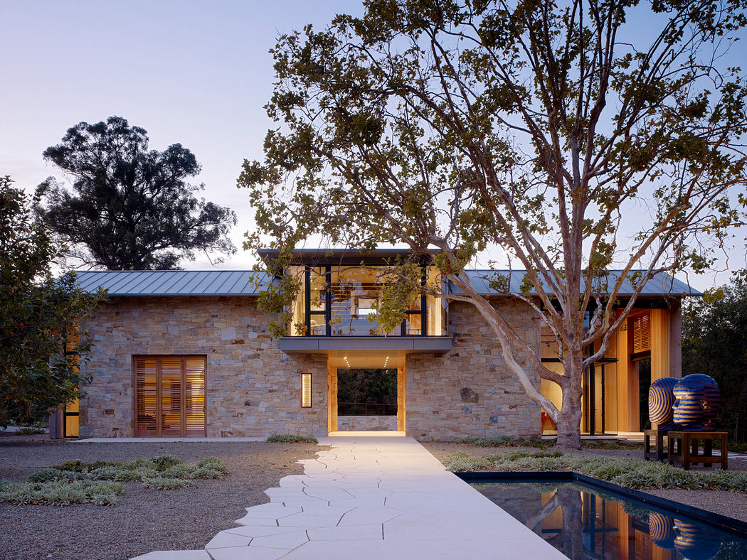 A modern ranch-style home with a stone exterior, metal roof, and private pool area.