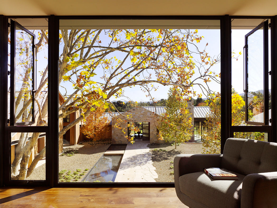 A cozy, modern interior framing a scenic autumn landscape with a stone path and buildings.
