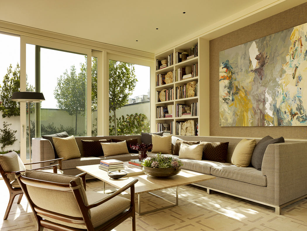 Spacious living room with large windows, neutral color palette, modern furniture.