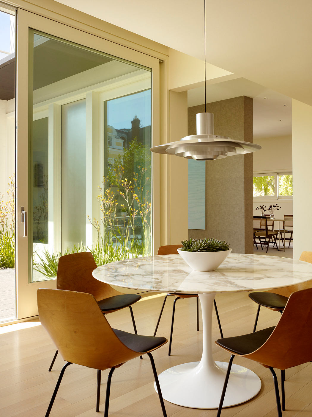 Sleek, modern dining area with a round marble table, pendant lighting, and stylish chairs.
