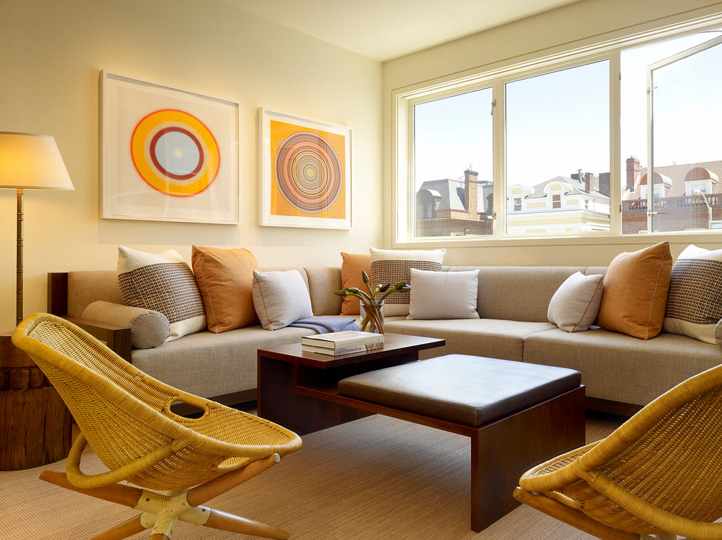 Bright, modern living room with geometric wall art, cozy sofa, and rattan chairs.