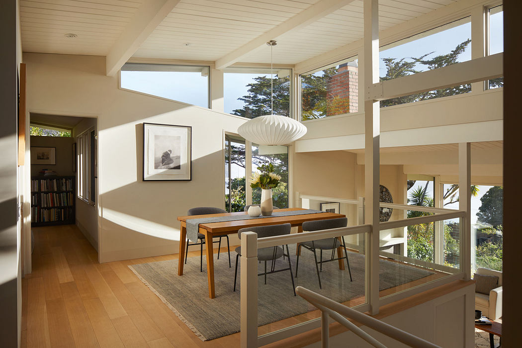 Warm-toned open-concept living space with wood furniture, natural light, and leafy views.