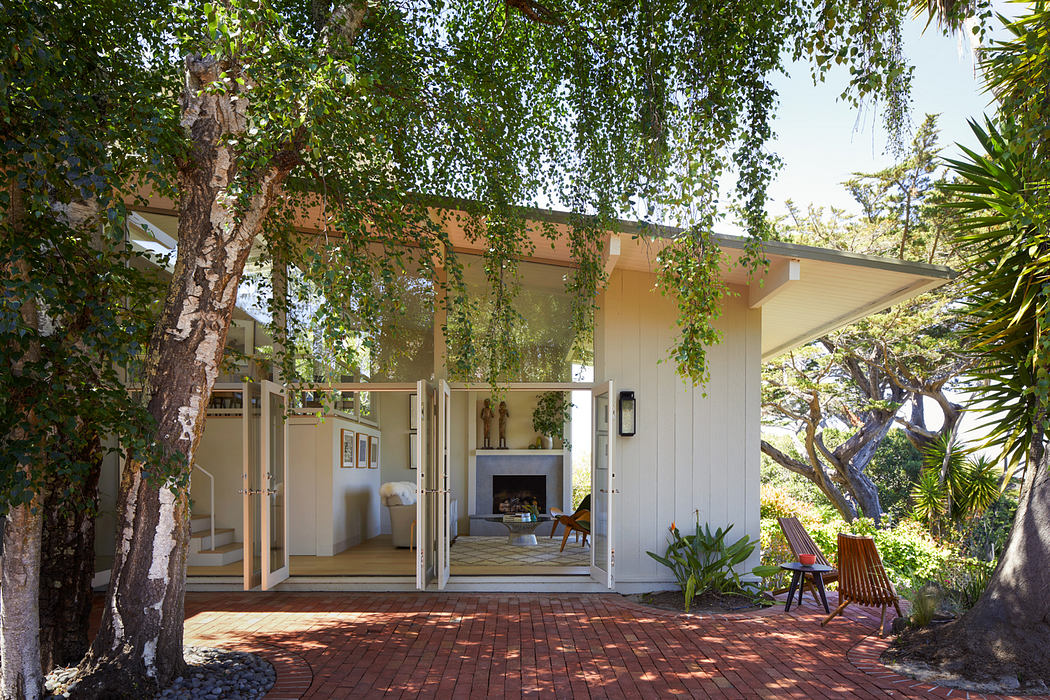 A cozy outdoor living space with a covered patio, brick floor, and lush greenery.