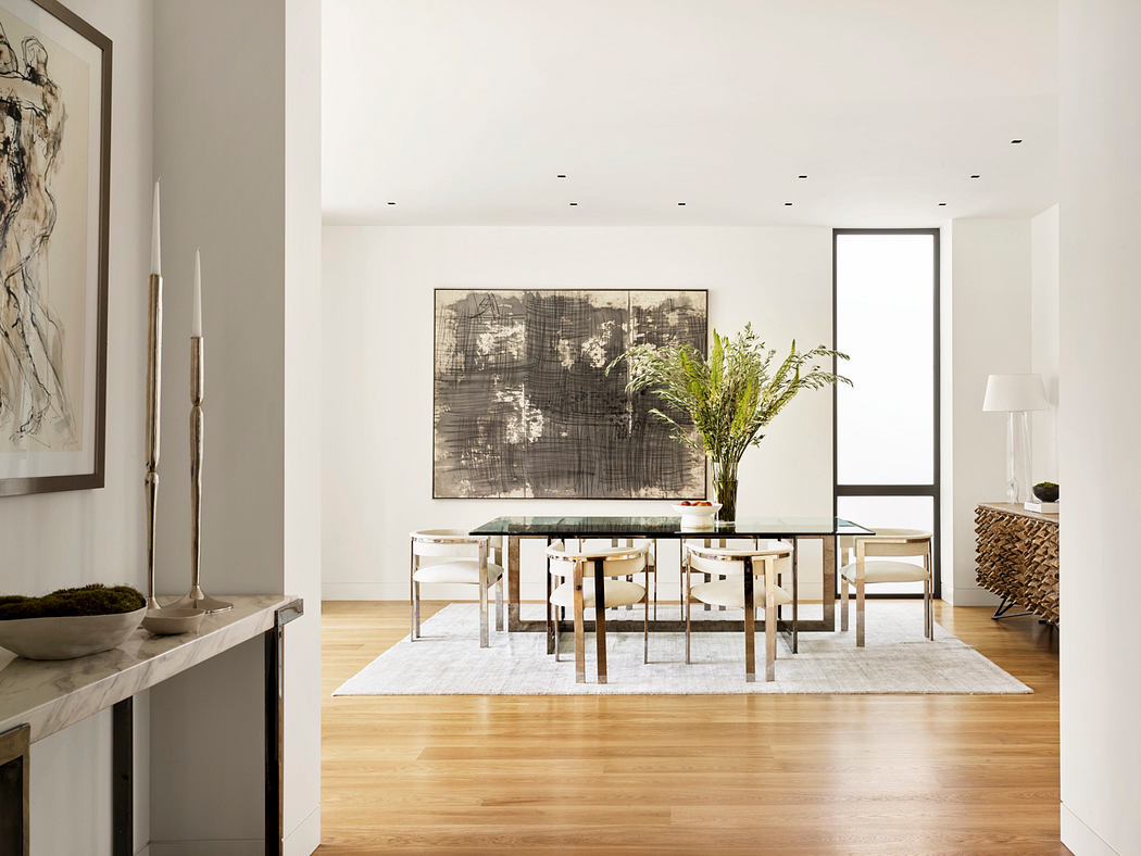 Modern, minimalist dining room with abstract artwork, glass table, and natural wood floors.