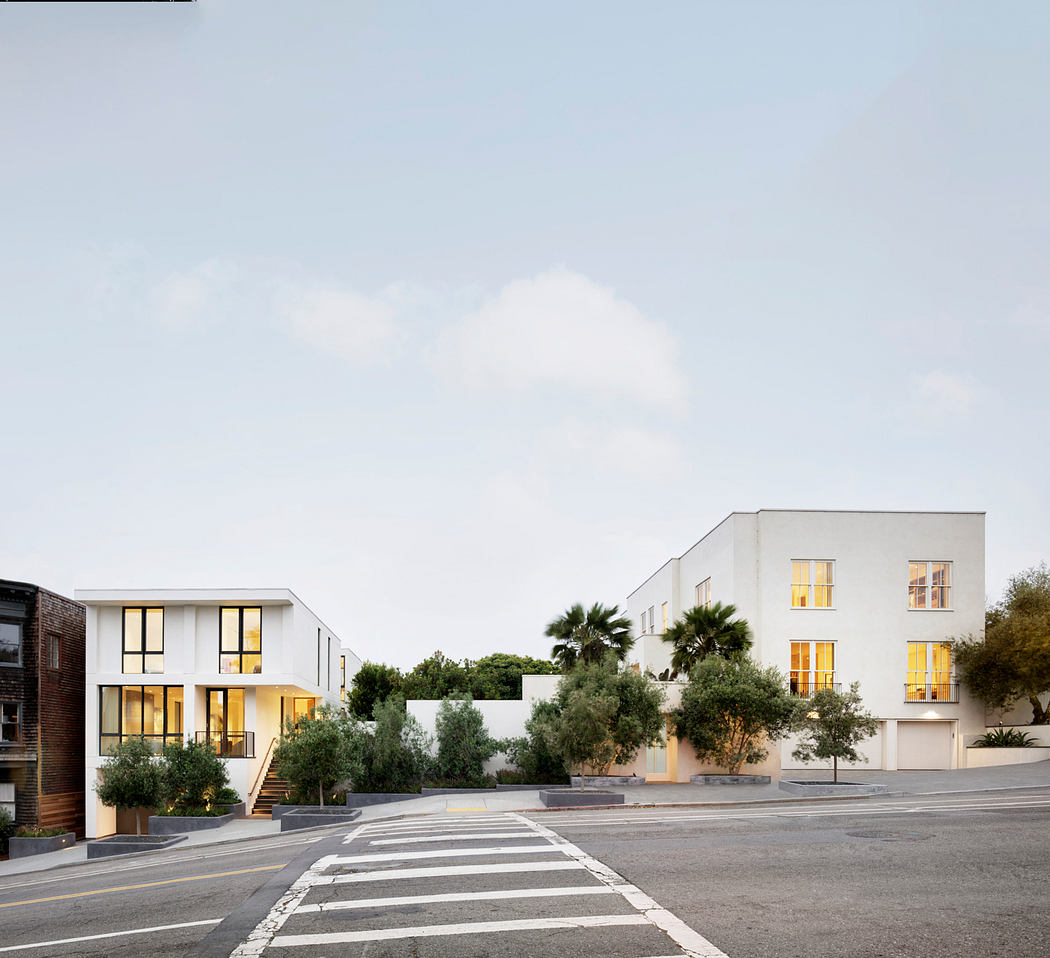 Modern buildings with clean lines, large windows, and palm trees lining the street.