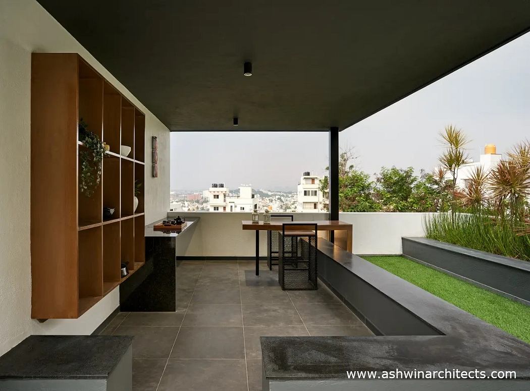Modern balcony with wood cabinetry, glass walls, and lush greenery overlooking a cityscape.