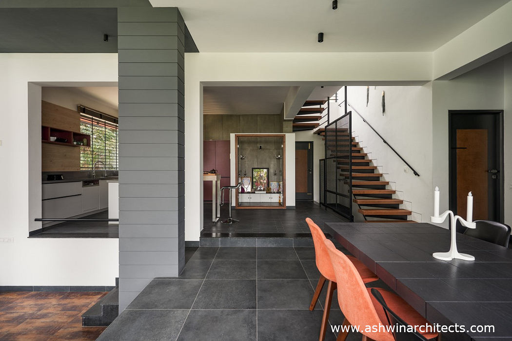 Spacious open-plan interior with modern kitchen, wood stairs, and black tile flooring.