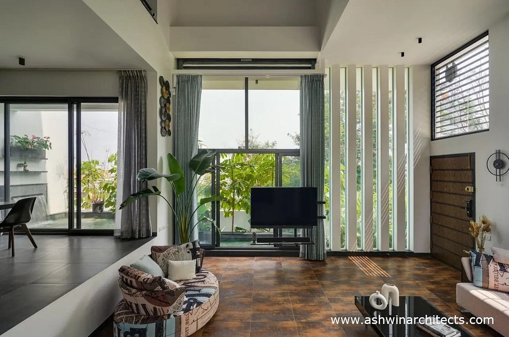 Bright, modern living space with large windows, wood-look tile, and lush greenery.